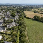 Vue aérienne d’un quartier résidentiel en bordure de terres agricoles illustrant les enjeux de la loi ZAN